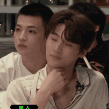 two young men are sitting next to each other and one has a green sticker on his shirt that says " y "