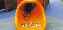 a person is going down an orange slide that says " sup girl " on it