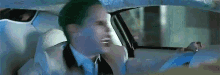 the joker is sitting in the back seat of a car with a plastic bag over his head .