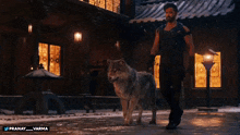 a man walking with a wolf in front of a building that says pranay varma on the bottom