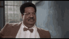 a man wearing a suit and bow tie is looking at the camera .