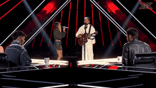 a man and a woman singing on a stage with x factor written on the bottom