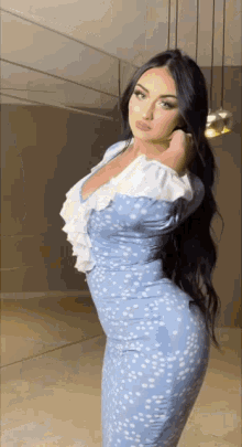 a woman in a blue dress is standing in front of a mirror