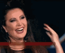a woman is smiling and making a funny face with her hands .