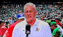 a man wearing a shirt that says a 's is talking into a microphone