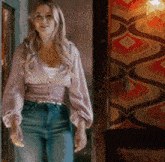 a woman is standing in a hallway wearing a purple sweater and jeans .