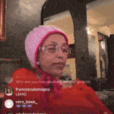 a woman wearing glasses and a pink hat is sitting in front of a mirror