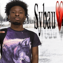 a man wearing a purple shirt with a wolf on it stands in front of a sybau logo