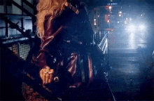 a woman in a leather jacket is standing in front of a train in a dark tunnel .