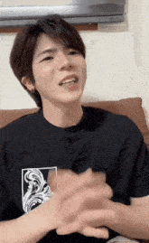 a young man sitting on a couch with his hands folded in front of a television that says 013