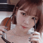 a close up of a woman holding a pair of glasses