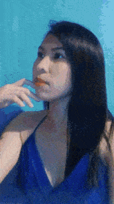 a woman in a blue dress has her hand on her face