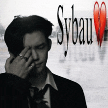a man covering his face with his hand with sybau written in the background