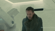 a man in a fur coat is standing in front of a white wall