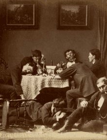 a group of men are gathered around a table with a white table cloth