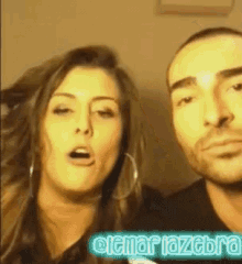 a man and a woman are posing for a picture and the woman is wearing hoop earrings and the man has a beard