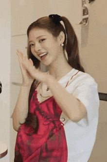 a woman wearing a red dress and a white shirt applauds