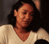 a woman is wearing a white sweater and a necklace and looking down .