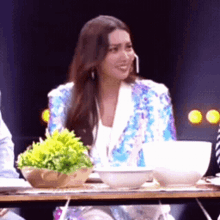 a woman in a sequined jacket is sitting at a table with bowls on it