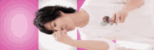a man in a white shirt is eating an ice cream cone on a pink and white background .