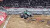 a monster jam truck is driving down a dirt track in front of a crowd