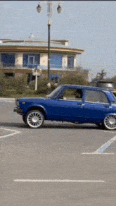 a blue car is parked in a parking lot next to a building