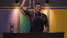 a man in an apron is standing behind a bar with his arm in the air
