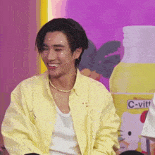 a man wearing a yellow shirt is smiling in front of a bottle of c-vitt