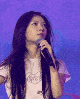 a woman singing into a microphone wearing a white shirt that says claire