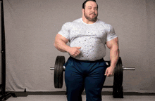 a man with a big belly is standing in front of a barbell and giving a thumbs up