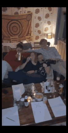 a group of people are sitting on a couch drinking