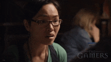 a woman wearing glasses and a green shirt with the words the gamers below her
