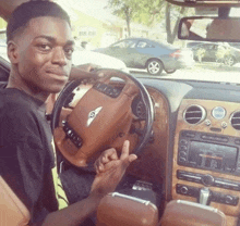 a young man sitting in a bentley car giving a middle finger
