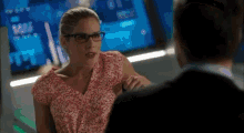 a woman wearing glasses is sitting next to a man in front of a computer screen .
