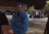 a man in a blue hoodie is standing in a parking lot