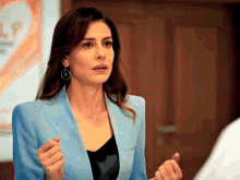 a woman in a blue jacket and earrings stands in front of a sign that says help