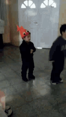 a young boy wearing a fish hat is dancing in a hallway