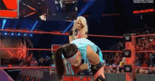 a woman is carrying another woman in a wrestling ring during a replay match .