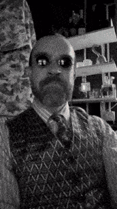 a black and white photo of a man wearing a vest and tie