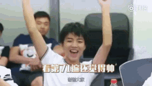 a young man is sitting in a chair with his arms up in the air .
