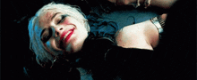 harley quinn is smiling while laying on the floor with her eyes closed .