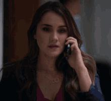 a woman talking on a cell phone with a necklace that says infinity