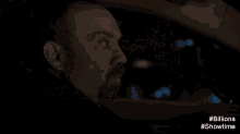 a car is driving down a street at night with the words # billions #showtime visible in the corner