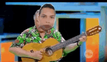 a man in a hawaiian shirt is playing a guitar