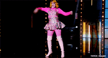 a woman in a pink and silver outfit is dancing on a stage with t4yce tumblr in the corner