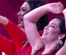 two women are dancing with their arms in the air and smiling