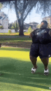 a man in shorts and sandals is dancing on a green field .