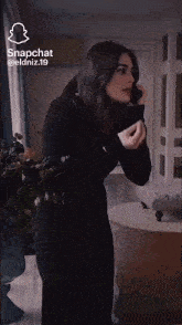 a woman in a black dress is talking on her phone