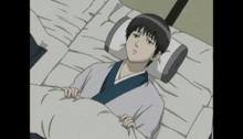 a man in a kimono is laying in a bed with a blanket and a pillow .