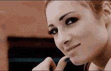 a close up of a woman 's face with her hand on her chin and looking at the camera .
